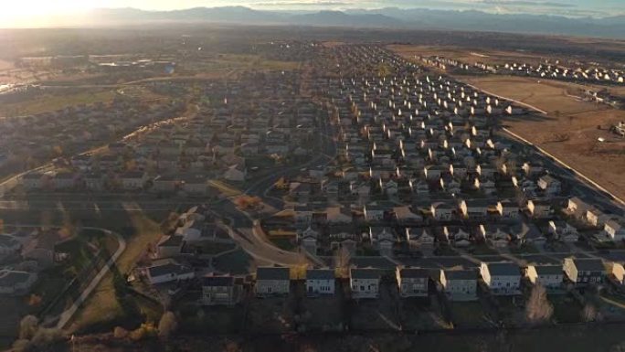 空中: 大型郊区小镇，日出时排屋被群山环绕