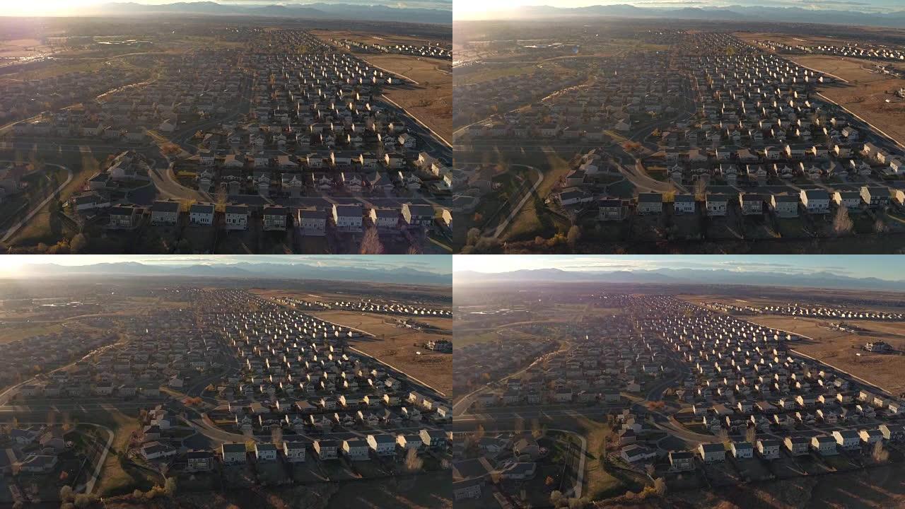 空中: 大型郊区小镇，日出时排屋被群山环绕