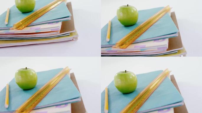 苹果，铅笔和刻度尺放在书堆上