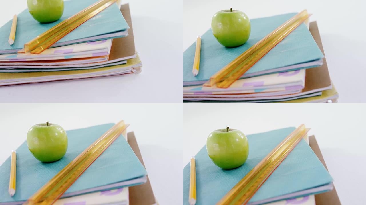 苹果，铅笔和刻度尺放在书堆上