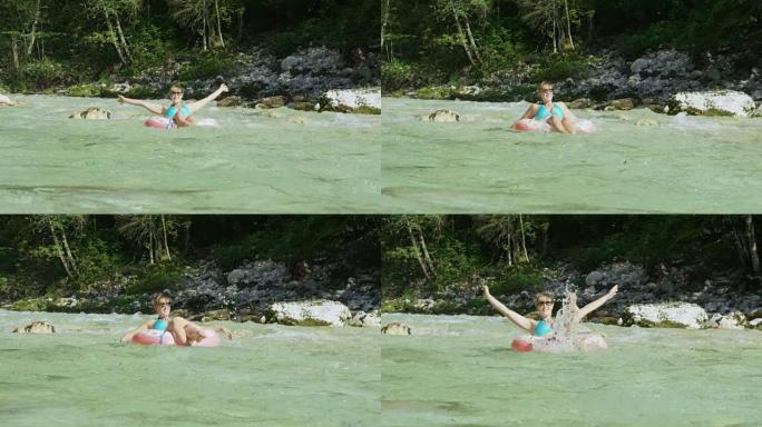 慢动作年轻女孩在甜甜圈漂浮物上滑翔在河水中飞溅
