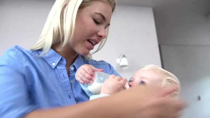 母亲给婴儿儿子一瓶牛奶