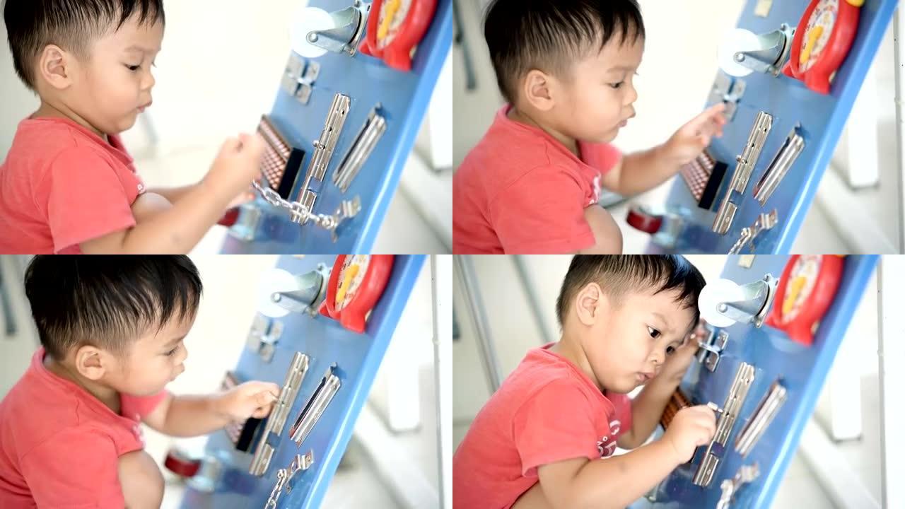 亚洲男婴在家玩DIY忙碌板。
