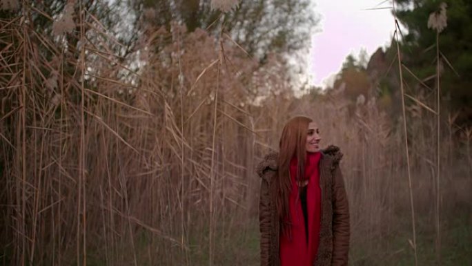年轻的红发女郎站在秋天的田野里微笑着