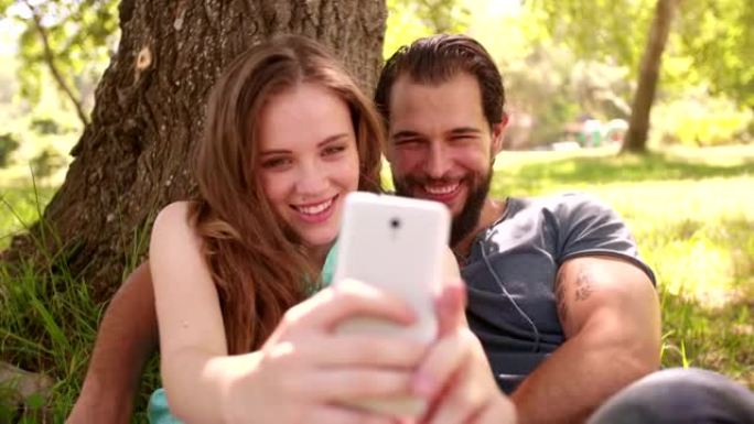 微笑的情侣在公园里用手机自拍