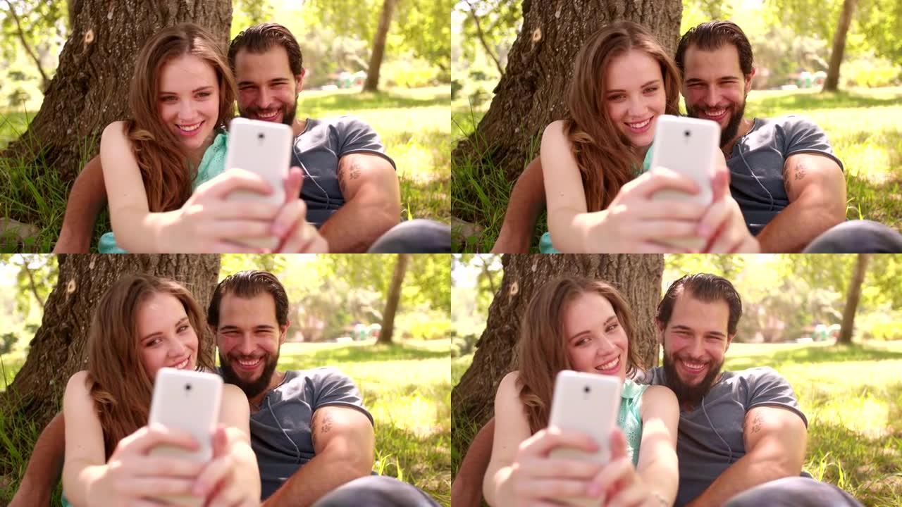 微笑的情侣在公园里用手机自拍