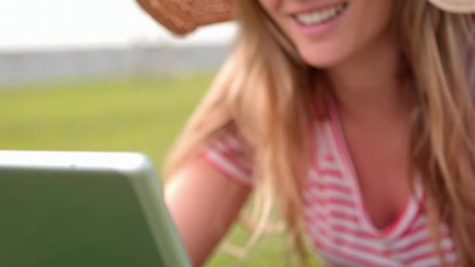 微笑的女人在公园里使用笔记本电脑