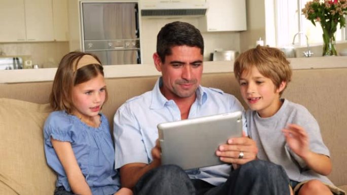 可爱的孩子和父亲一起在沙发上使用平板电脑