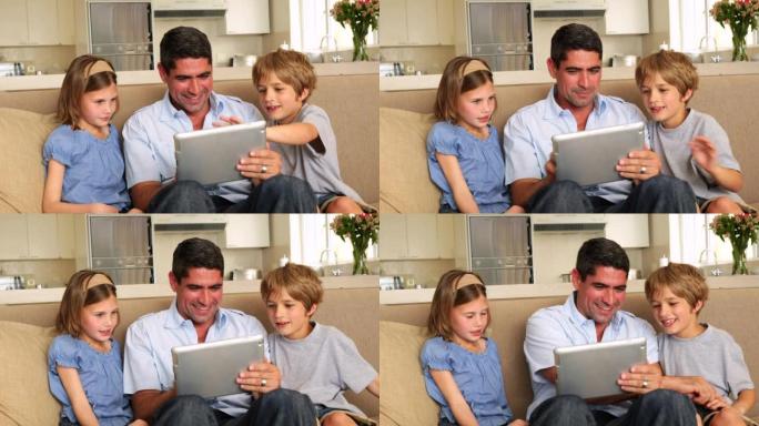 可爱的孩子和父亲一起在沙发上使用平板电脑