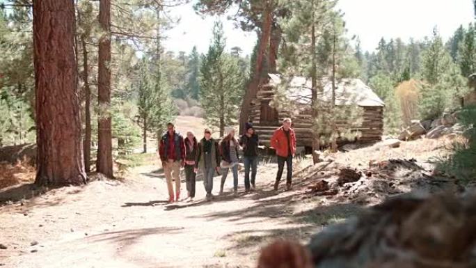 六个朋友走过森林中的小木屋，走向相机