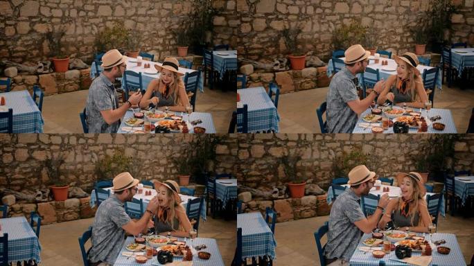 年轻的游客夫妇在希腊小酒馆里吃饭很开心