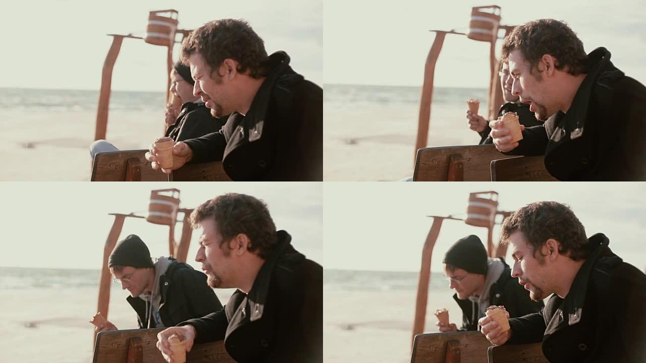 两个年轻人坐在岸边的木凳上吃冰淇淋和说话