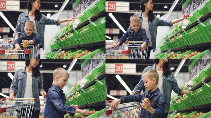 年轻的家庭母亲和儿子在杂货店买水果，他们拿梨和猕猴桃放在手推车上。快乐的顾客和超市概念。