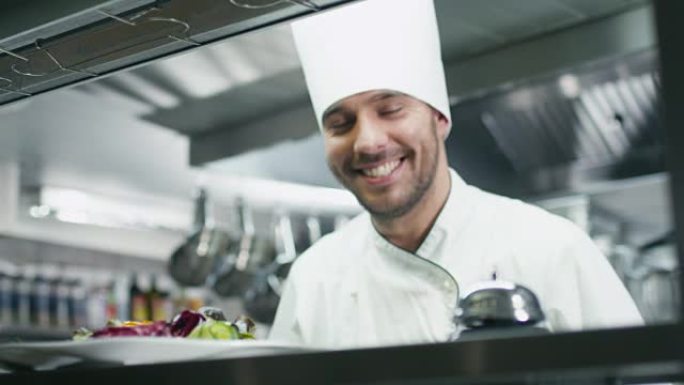 餐厅或酒店的商业厨房里快乐的专业厨师正在供应沙拉。