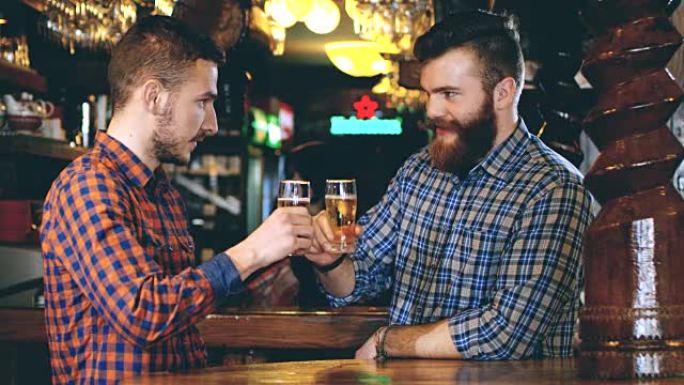 SLO MO两个年轻人在酒吧里用啤酒敬酒