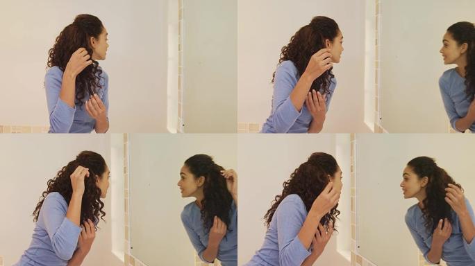 年轻女子站在镜子前做头发4K 4k