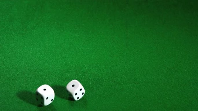 白色骰子在绿色桌子上滚动