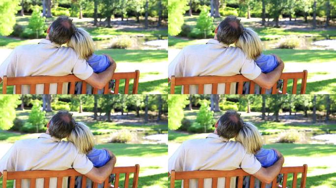 深情的夫妇坐在公园的长凳上