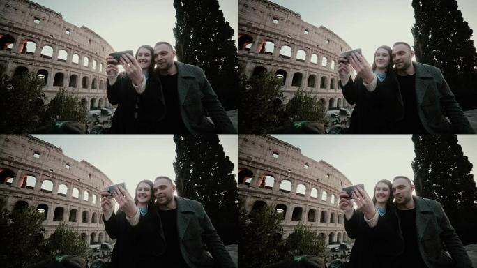 快乐的旅行夫妇一起在意大利罗马竞技场附近的智能手机上拍照留念