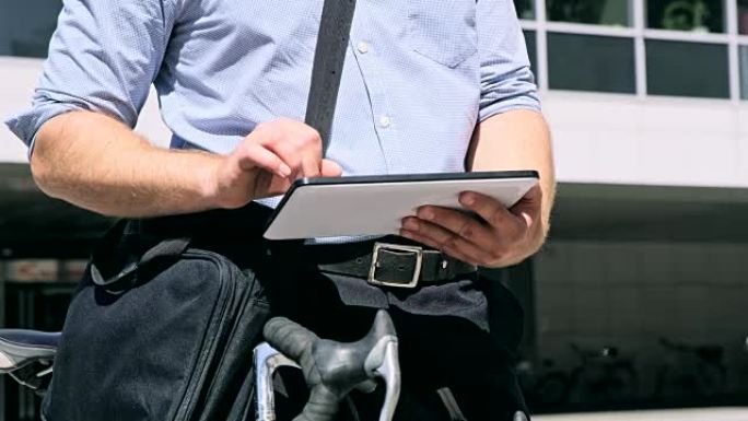 穿着衬衫的DS男子在办公楼前使用数字平板电脑