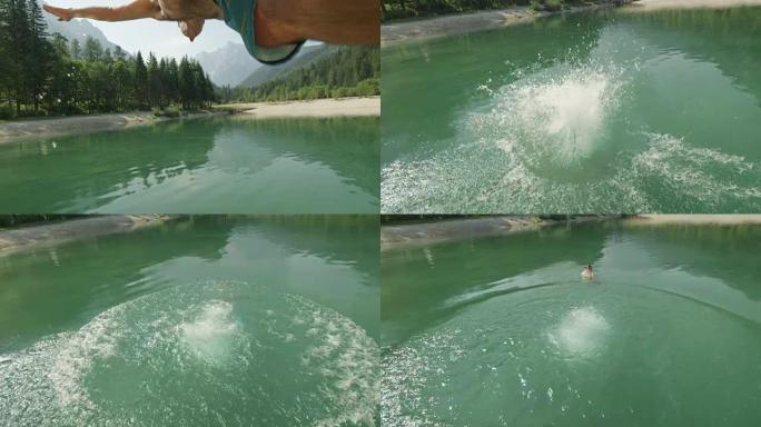 慢动作: 穿着泳衣的年轻人在阳光明媚的夏天跳入美丽的山湖