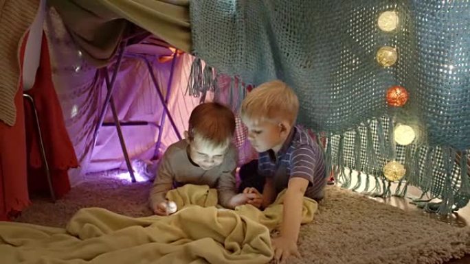 可爱的男孩在游戏帐篷中使用平板电脑