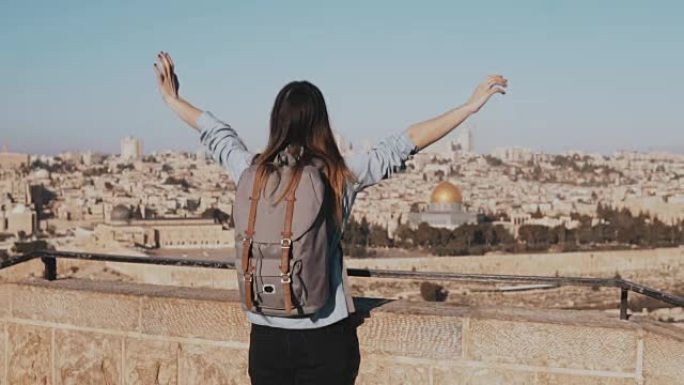 快乐的高加索女孩奔跑，双臂张开。以色列的景色，耶路撒冷老城。兴奋的女游客。慢动作