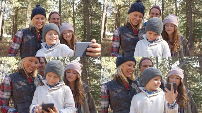 男孩在森林里用智能手机拍摄家庭自拍照