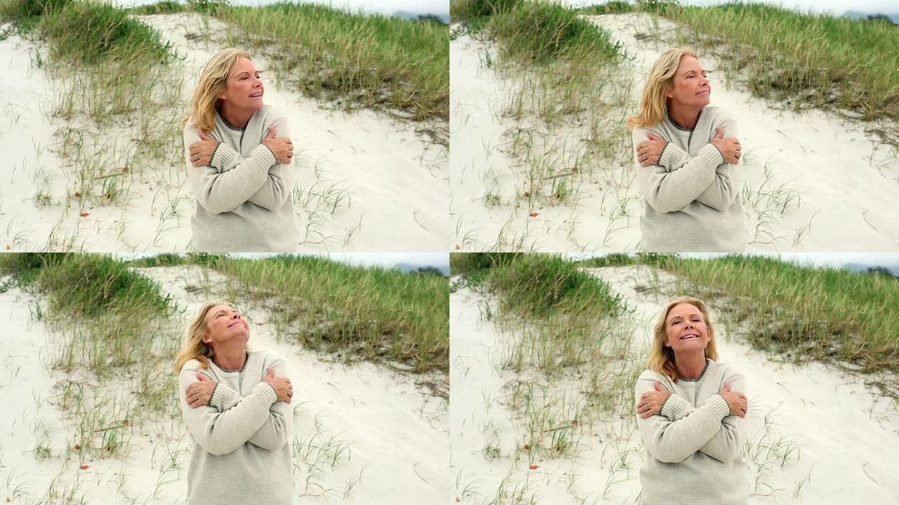 微笑的退休妇女在沙滩上瑟瑟发抖