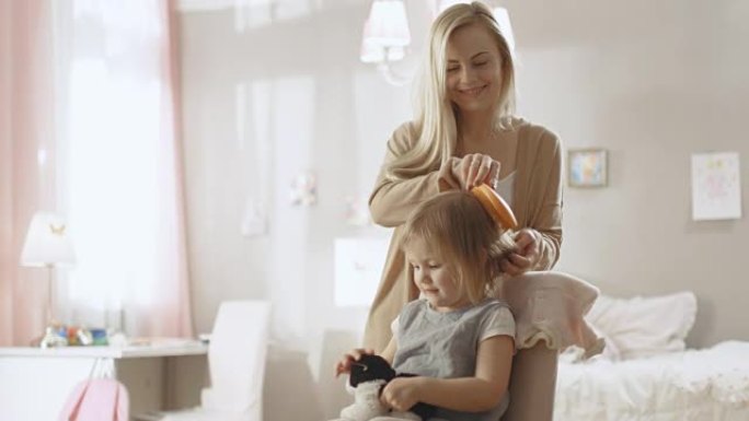 可爱的年轻母亲为她可爱的金发小女儿梳头。慢动作。