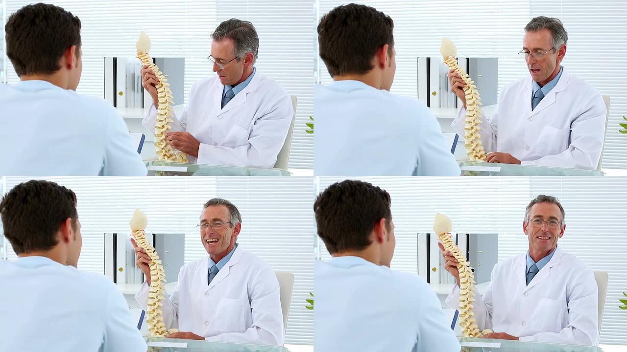 成熟的医生和他的病人谈论脊柱模型