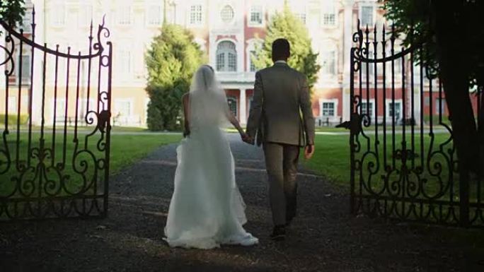新娘和新郎正走向公园的豪宅。