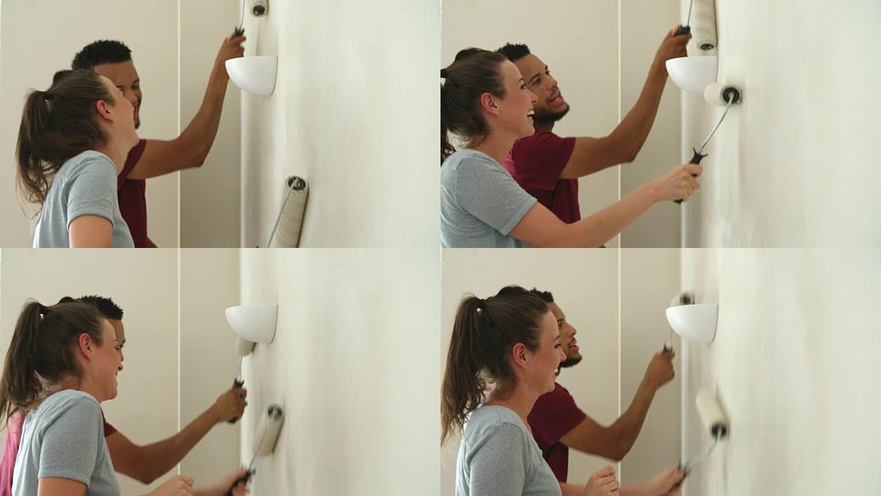 年轻夫妇用油漆滚筒装饰房屋，特写