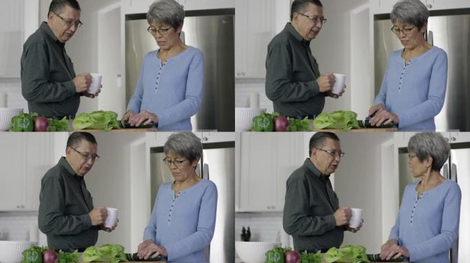 年长的族裔夫妇在厨房里切碎蔬菜
