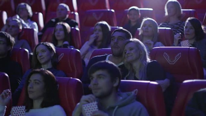 年轻的浪漫夫妇正在电影院观看电影放映。