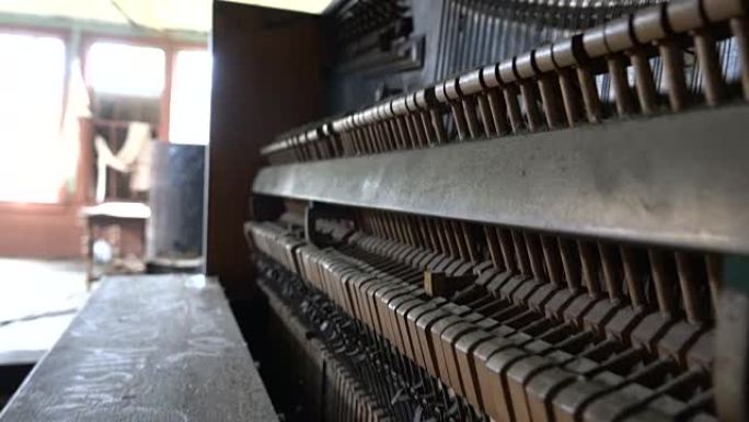 特写: 在废弃的房子里用旧的腐烂钢琴敲击琴弦