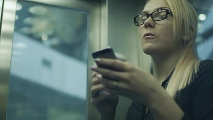 女人在电梯里喝咖啡和使用手机