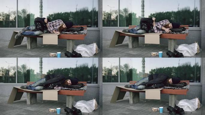 一个无家可归的年轻人试图穿着夹克衫睡在人行道的长椅上