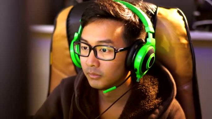 亚洲男子在咖啡馆用绿色游戏耳机玩游戏