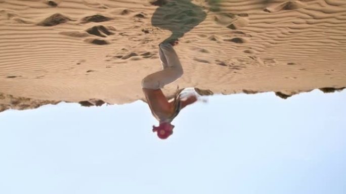 年轻的运动员在沙漠中做360度后空翻