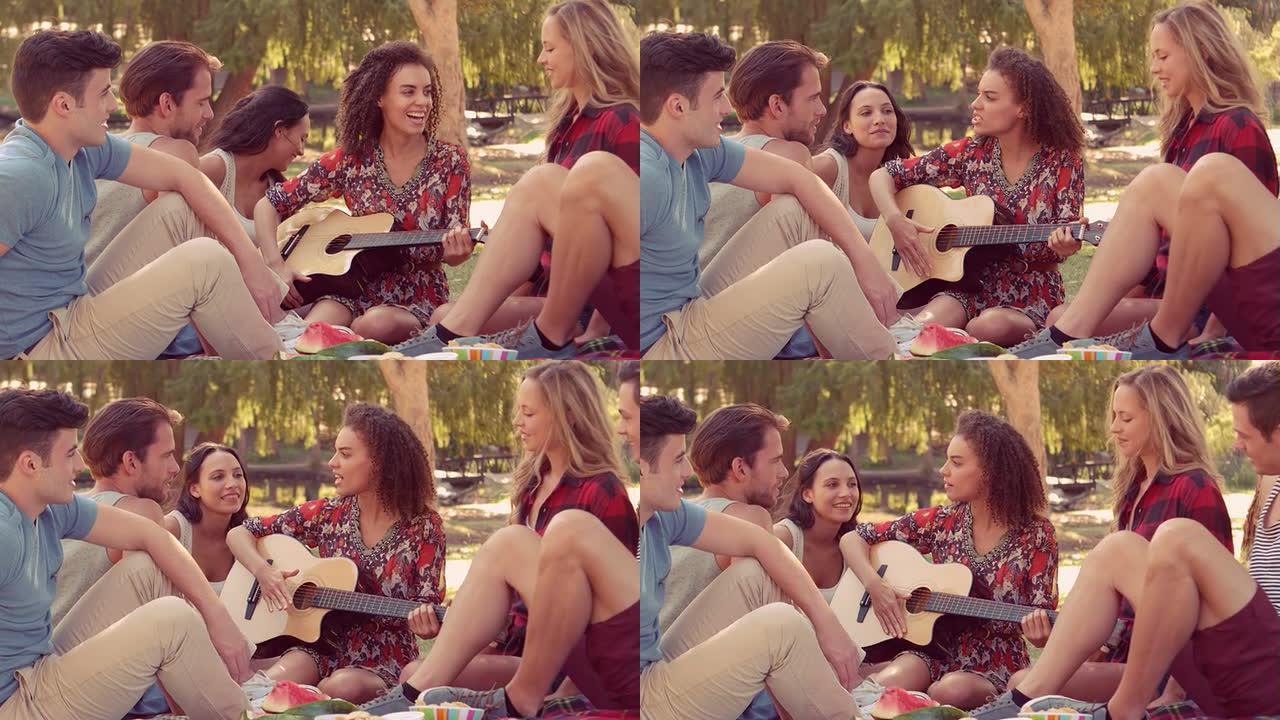 时髦的女人和她的朋友在公园弹吉他