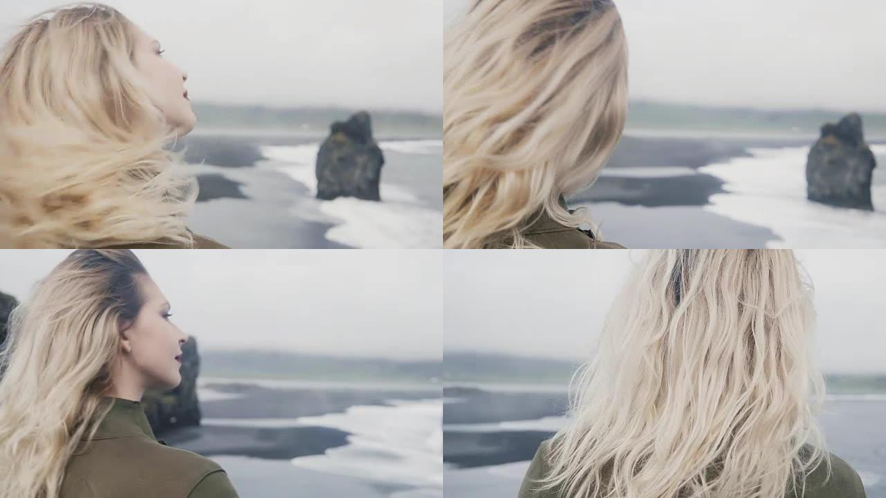 年轻的金发女子站在海边，在阴天看着冰岛的巨魔脚趾