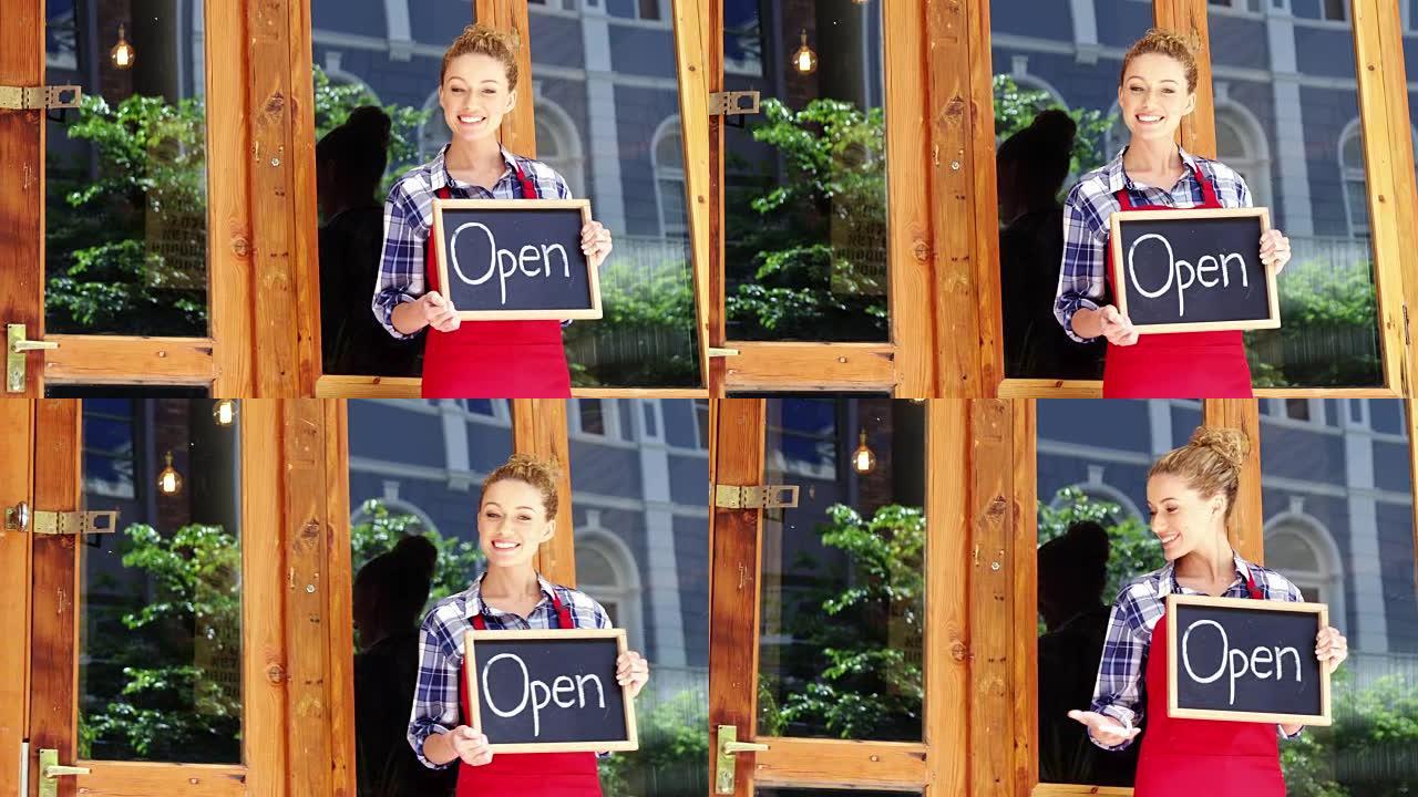 微笑的女服务员站在门外，在咖啡馆里开着招牌