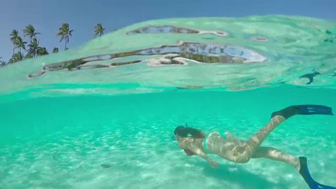 4k慢动作半水下特写: 快乐的年轻女子暑假在天堂游泳图片完美的绿松石蓝色泻湖走向热带岛屿