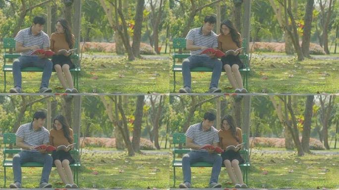 快乐的年轻夫妇坐在公园长椅上一起看书。