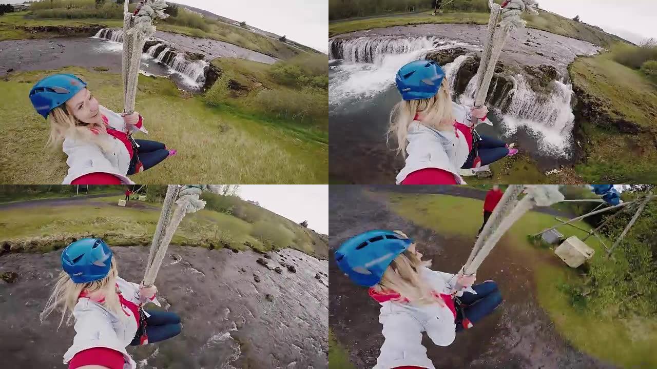年轻美女在蹦极上滑下的动作相机上自拍，穿过河上的绳索