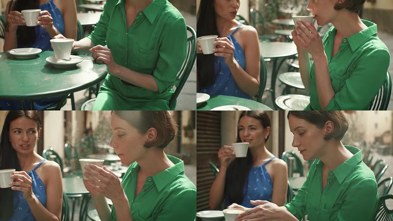 两个穿着轻便夏装的迷人年轻女性在街头咖啡店放松、交谈和喝咖啡。