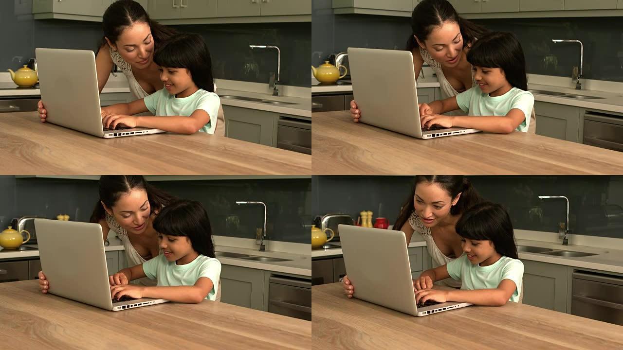 幸福的母女在厨房里使用笔记本电脑