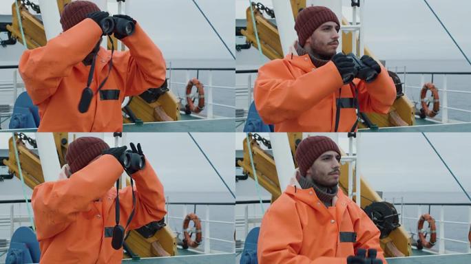 穿着防护外套的商业渔船船长透过双筒望远镜看