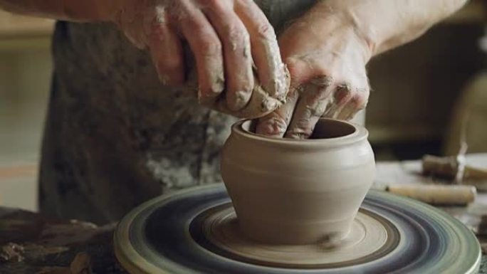 用专业工具在投掷轮上旋转半成品陶瓷锅和手切割粘土的特写镜头。创造了eathenware和传统陶器概念